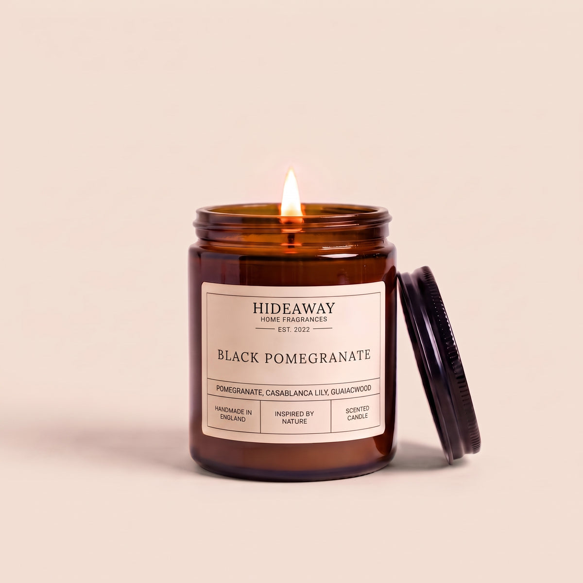Black pomegranate aromatherapy candle in a dark amber glass container by Hideaway Home Fragrances