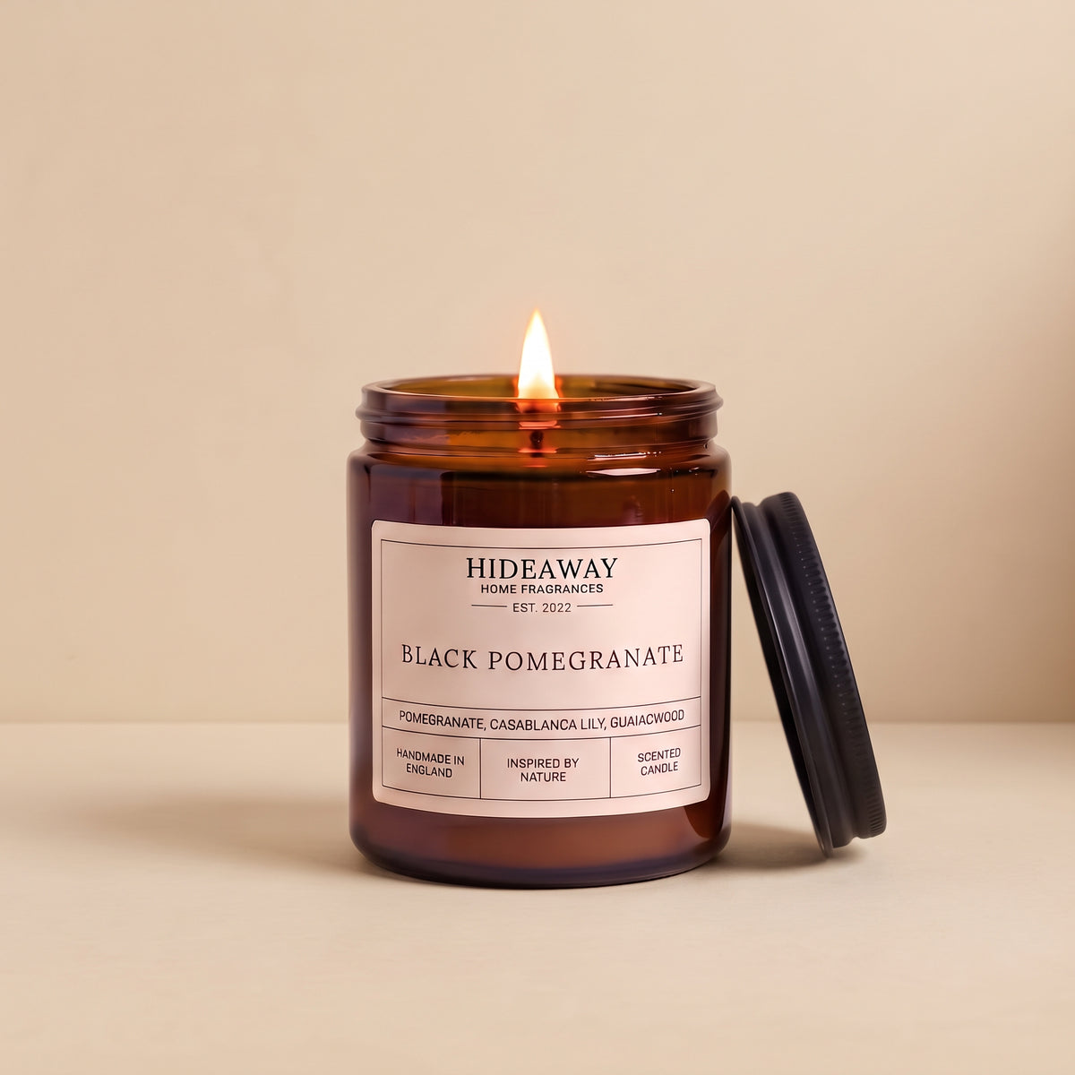 Black pomegranate aromatherapy candle in a dark amber glass container by Hideaway Home Fragrances