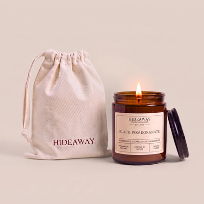 Hand-poured black pomegranate scented candle in a warm amber glass jar by Hideaway Home Fragrances