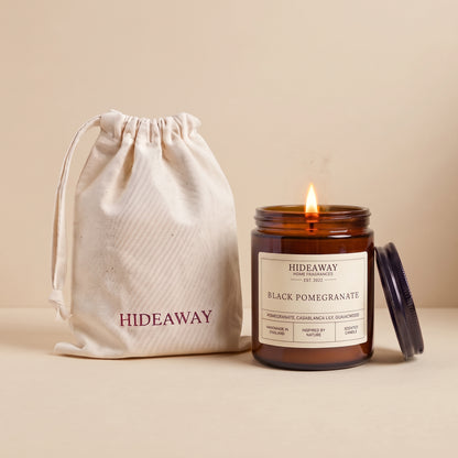Hand-poured black pomegranate scented candle in a warm amber glass jar by Hideaway Home Fragrances