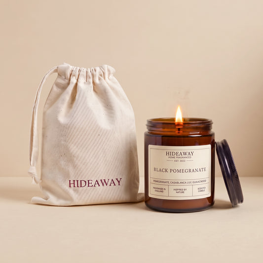 Hand-poured black pomegranate scented candle in a warm amber glass jar by Hideaway Home Fragrances
