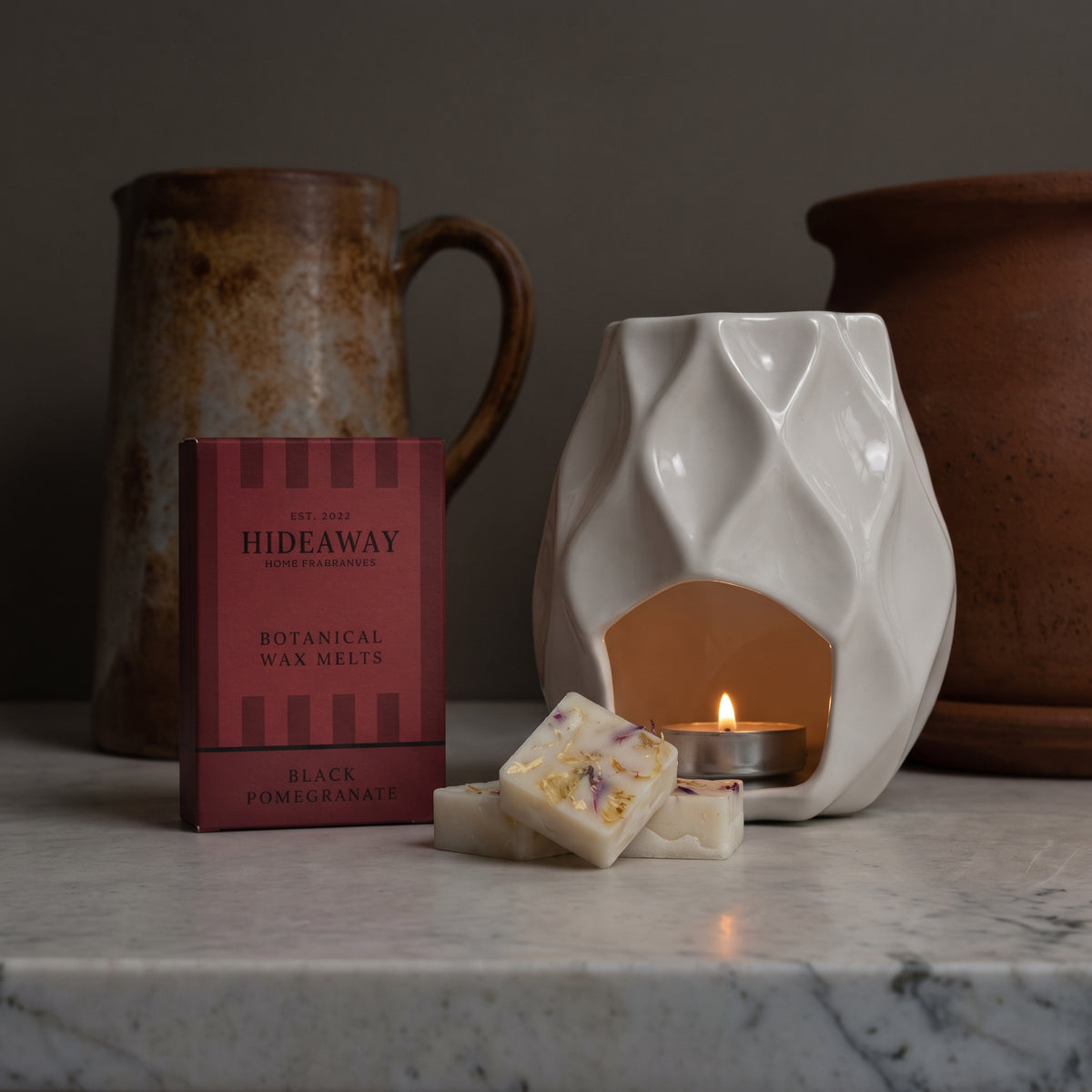 Luxury black pomegranate botanical soy wax melt bar by Hideaway Home Fragrances topped with dark botanical botanicals