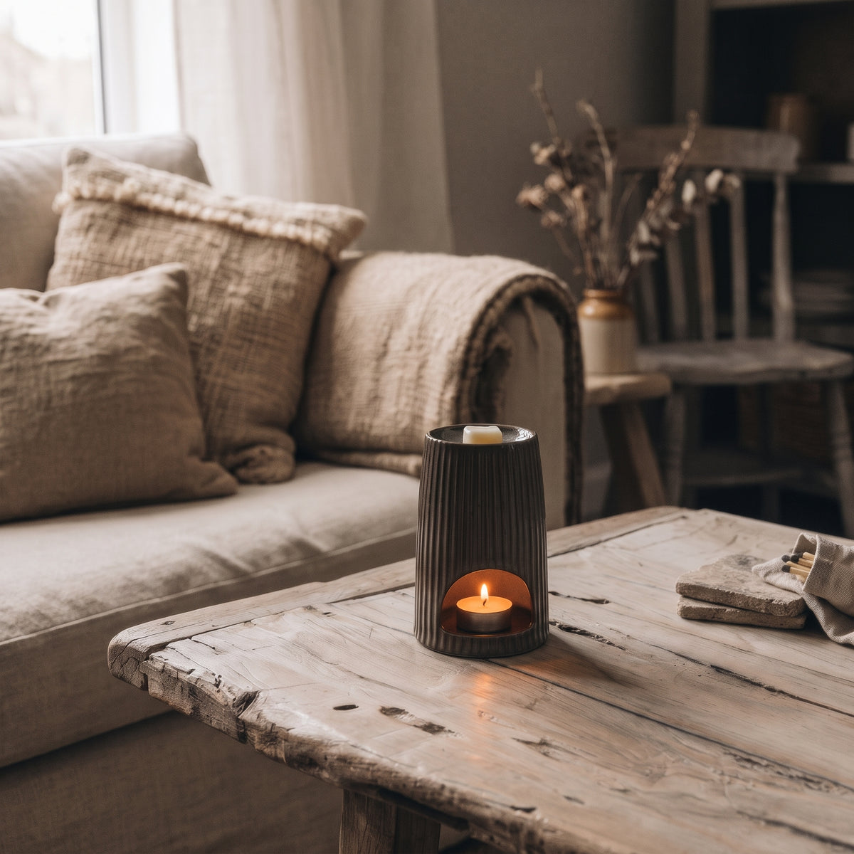 Hideaway Home Fragrances Bronze Ribbed Ceramic Wax Melt Burner styled on a rustic wooden shelf alongside dried botanicals in a cozy, warm-toned living room.