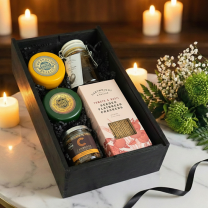 Close up of caramelised peanuts and wax-coated cheese truckle next to a jar of artisan chutney.