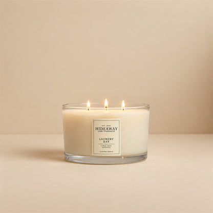Lit Laundry Day 3 wick soy candle by Hideaway Home Fragrances burning on a clean table for a fresh home atmosphere