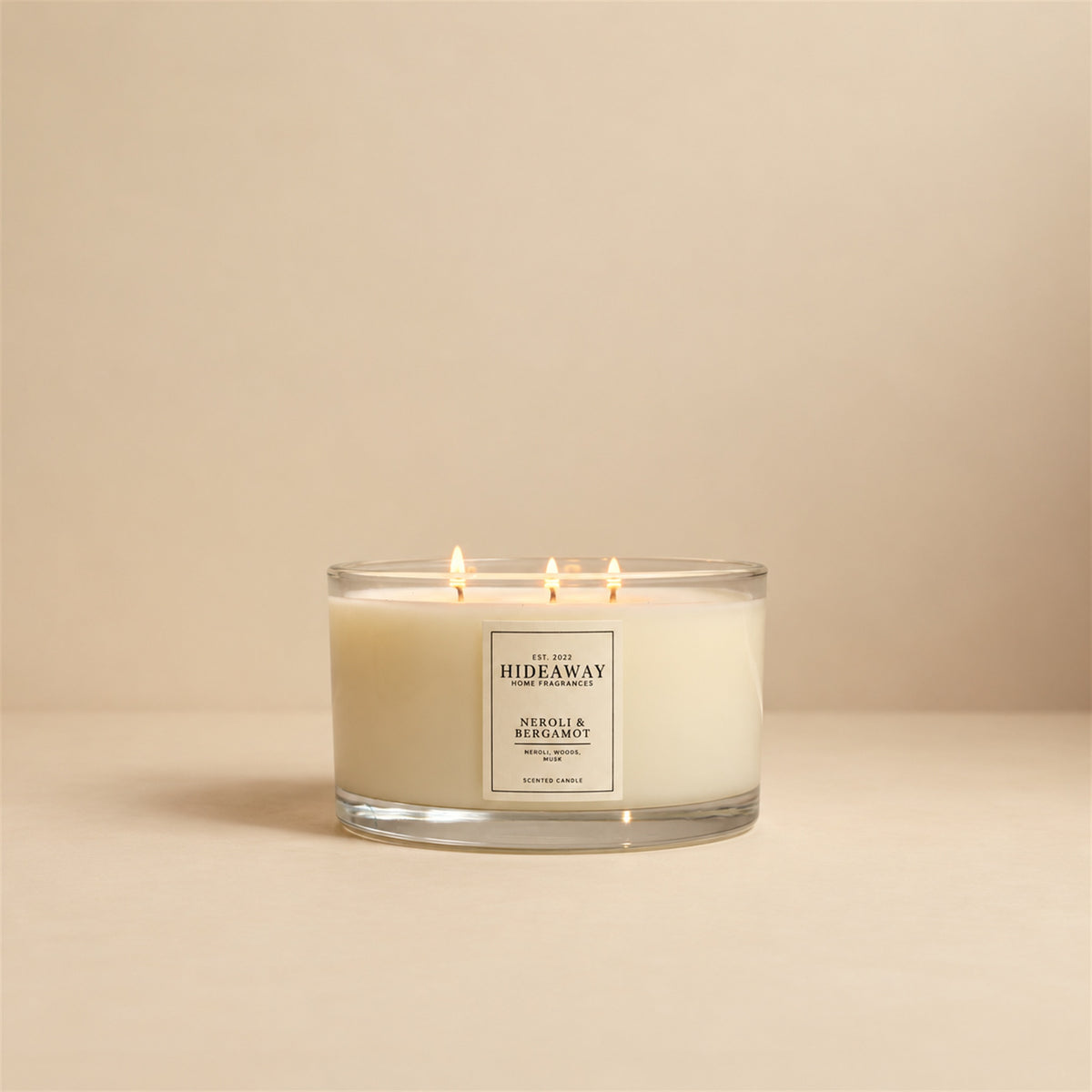 Lit Neroli and Bergamot 3 wick soy candle by Hideaway Home Fragrances burning on a coffee table for an uplifting home atmosphere
