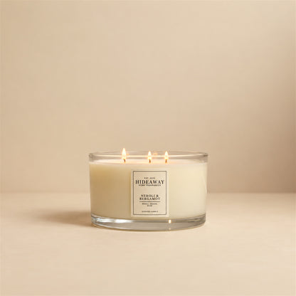 Lit Neroli and Bergamot 3 wick soy candle by Hideaway Home Fragrances burning on a coffee table for an uplifting home atmosphere