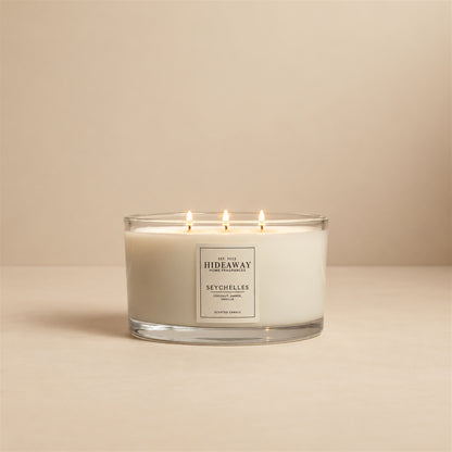 Lit Seychelles 3 wick soy candle by Hideaway Home Fragrances burning on a bathroom shelf for a relaxed spa atmosphere
