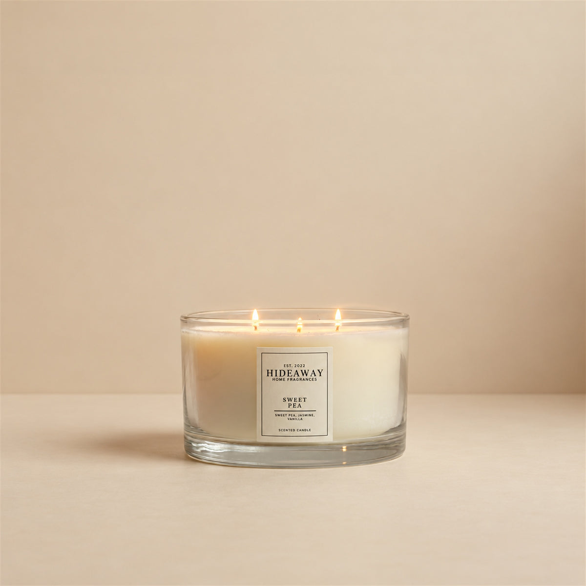 Lit Sweet Pea 3 wick soy candle by Hideaway Home Fragrances burning on a bedroom bedside table for a fresh floral aroma