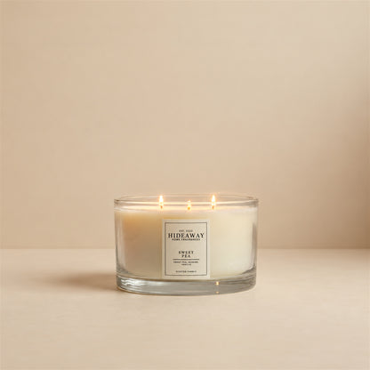 Lit Sweet Pea 3 wick soy candle by Hideaway Home Fragrances burning on a bedroom bedside table for a fresh floral aroma