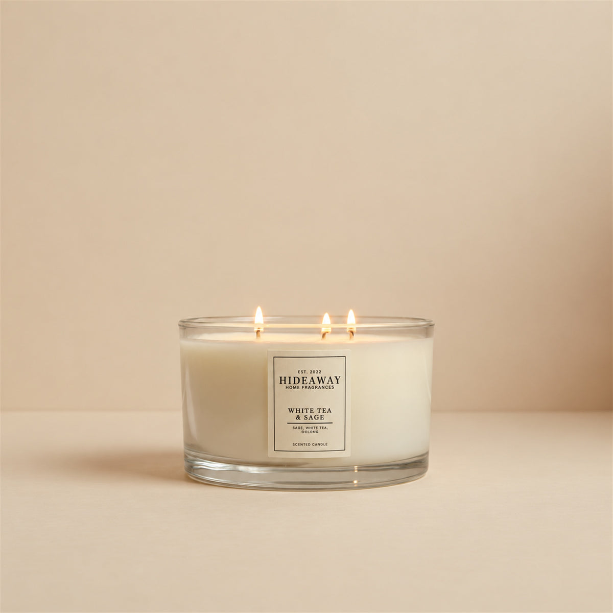 Lit White Tea and Sage 3 wick soy candle by Hideaway Home Fragrances burning on a living room shelf for a relaxing home atmosphere