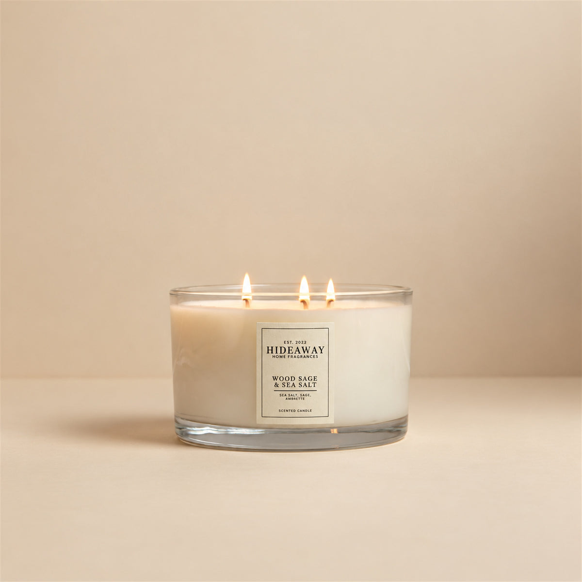 Lit Wood Sage and Sea Salt 3 wick soy candle by Hideaway Home Fragrances burning on a living room mantlepiece for a fresh coastal atmosphere