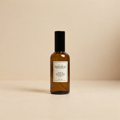 Person misting the herbal Hideaway Home Fragrances bay and rosemary room spray to freshen a bedroom space.