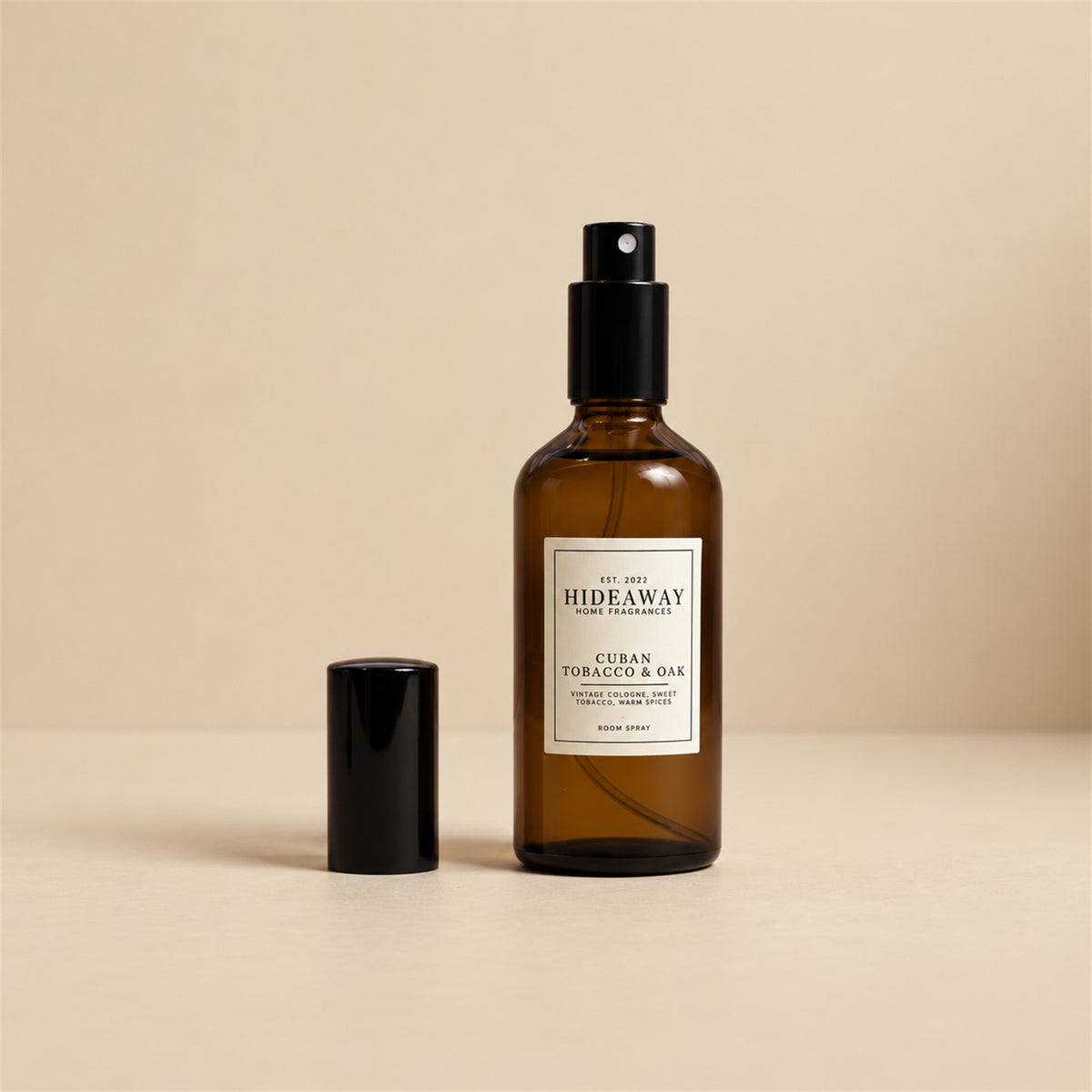 Hand spraying Hideaway Home Fragrances cuban tobacco and oak room spray into a room to release warm clove, tobacco, and musk aromas.