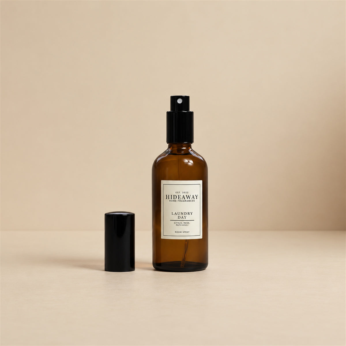 Hand spraying the Hideaway Home Fragrances laundry day room spray to diffuse clean aromas of peach, geranium, and warm vanilla into living areas.