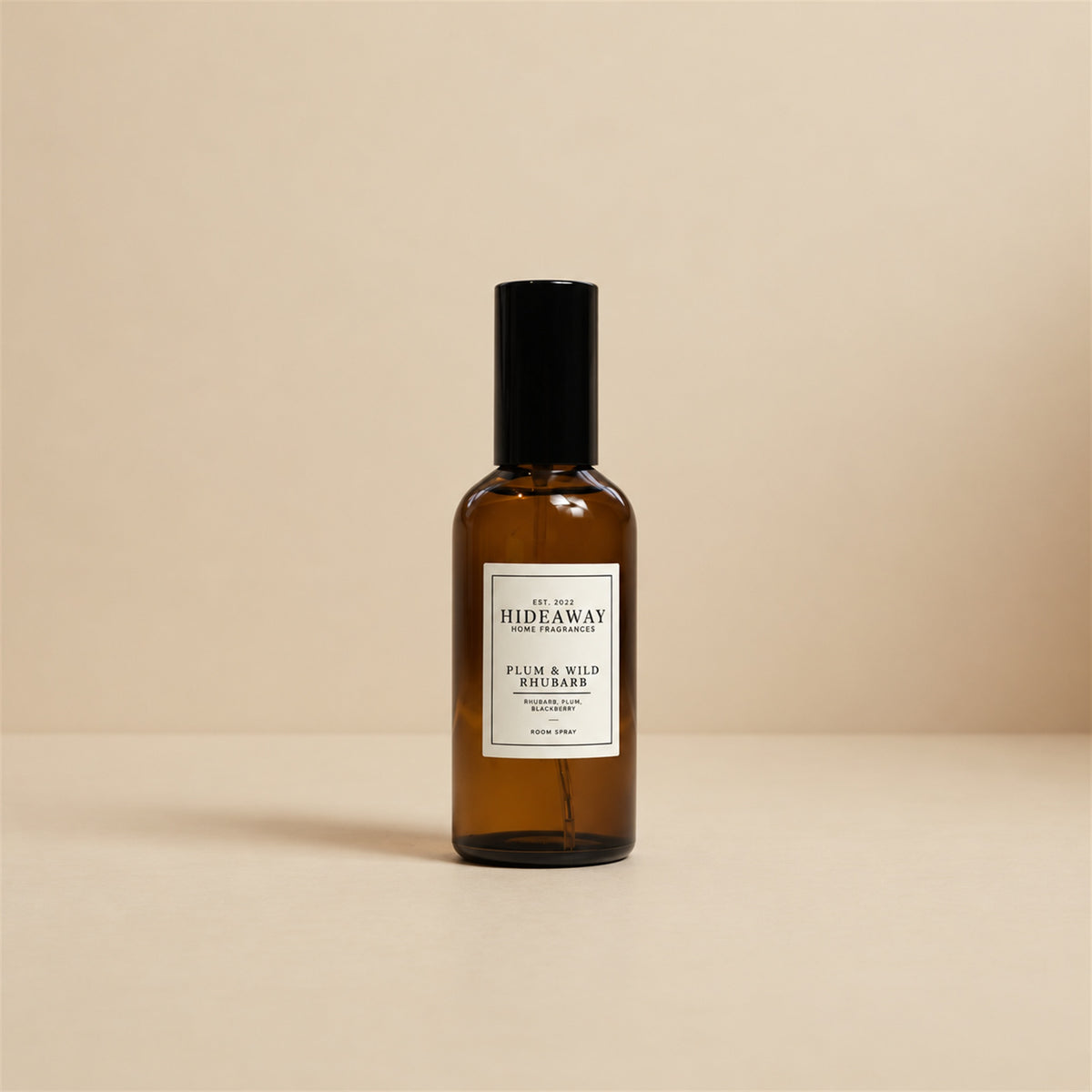 Hideaway Home Fragrances plum and wild rhubarb room spray styled on a wooden tabletop alongside a bowl of fresh seasonal orchard fruit.