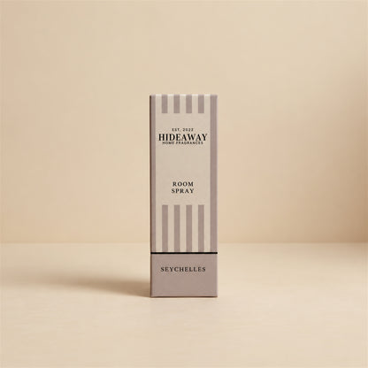 Packaged Hideaway Home Fragrances seychelles room spray bottle standing next to its luxury gift box showcasing warm vanilla and amber home fragrance notes.