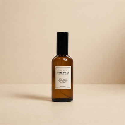 Hideaway Home Fragrances spa day room spray styled on a marble bathroom vanity beside rolled white towels and eucalyptus stems.