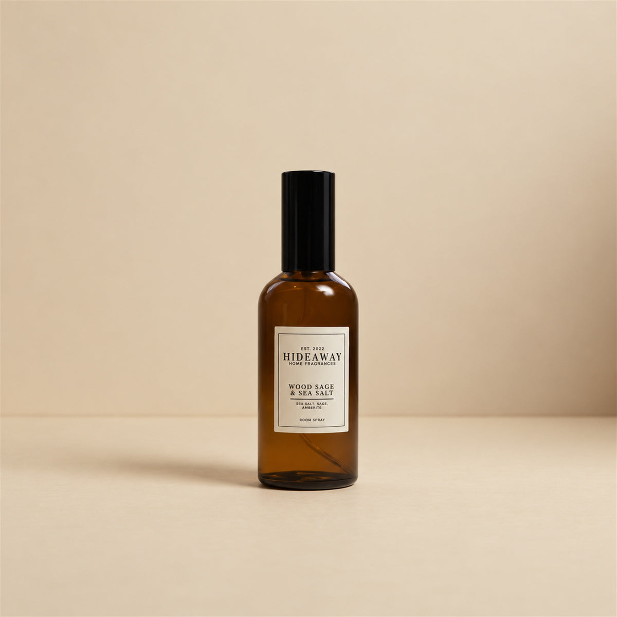 Hideaway Home Fragrances wood sage and sea salt room spray styled on a natural driftwood shelf beside white coastal pebbles and textured linen.