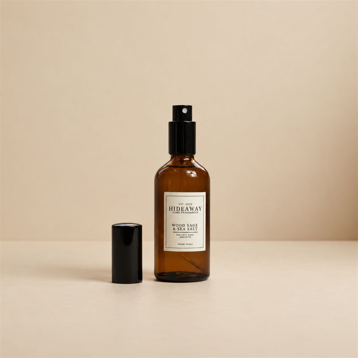 Fine mist spraying from the Hideaway Home Fragrances wood sage and sea salt room spray bottle to diffuse fresh ozone, grapefruit, and ambergris notes into the air.