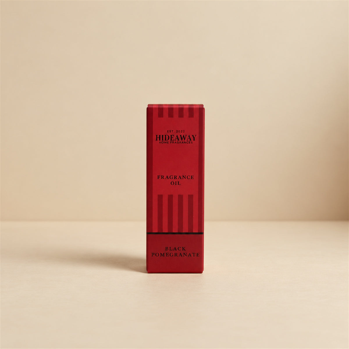 Packaged Hideaway Home Fragrances fragrance oil bottle standing beside its luxury retail box highlighting fruity pomegranate and woody guaiac notes.