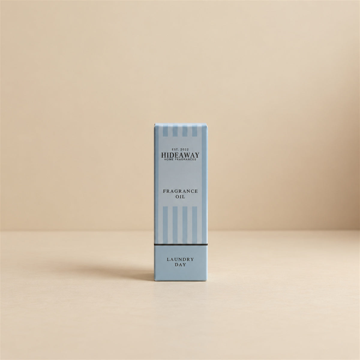 Packaged Hideaway Home Fragrances laundry day fragrance oil bottle standing beside its luxury retail box highlighting orange, geranium, and warm vanilla notes.