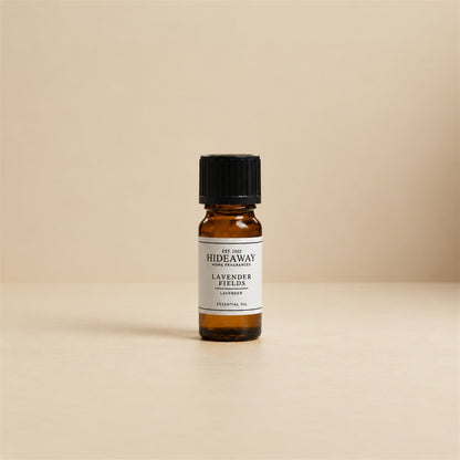 Glass dropper dispensing Hideaway Home Fragrances lavender fields fragrance oil into an aroma diffuser beside dried lavender sprigs for sleep relaxation.