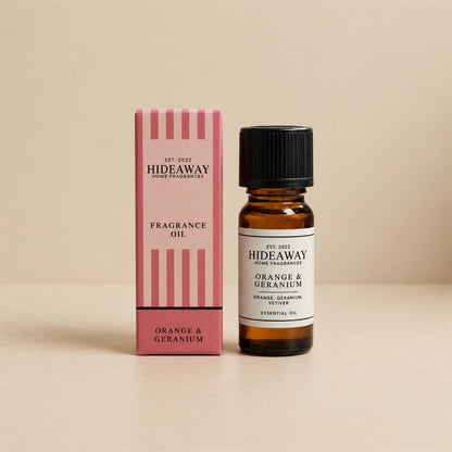 Hideaway Home Fragrances orange and geranium fragrance oil bottle standing against a seamless neutral studio backdrop.