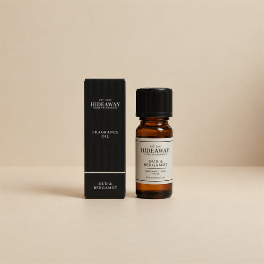 Hideaway Home Fragrances oud and bergamot fragrance oil bottle standing against a seamless neutral studio backdrop.