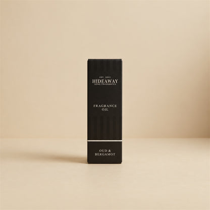 Packaged Hideaway Home Fragrances oud and bergamot fragrance oil bottle standing beside its luxury retail box highlighting citrus, precious woods, and musk notes.