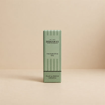 Packaged Hideaway Home Fragrances pear and white freesia fragrance oil bottle shown beside its luxury gift box highlighting delicate melon, rose, and patchouli notes.