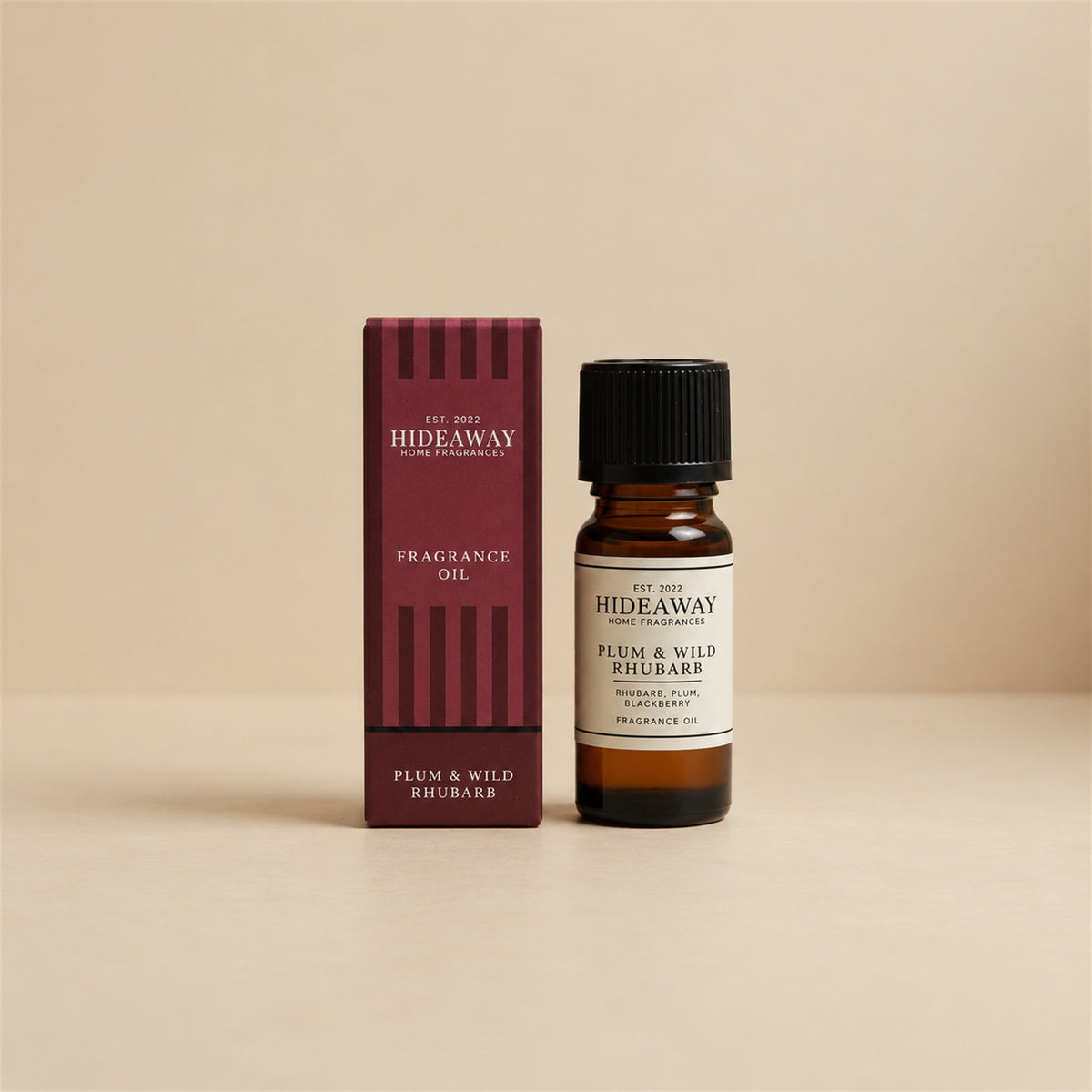 Hideaway Home Fragrances plum and wild rhubarb fragrance oil bottle standing against a seamless neutral studio backdrop.