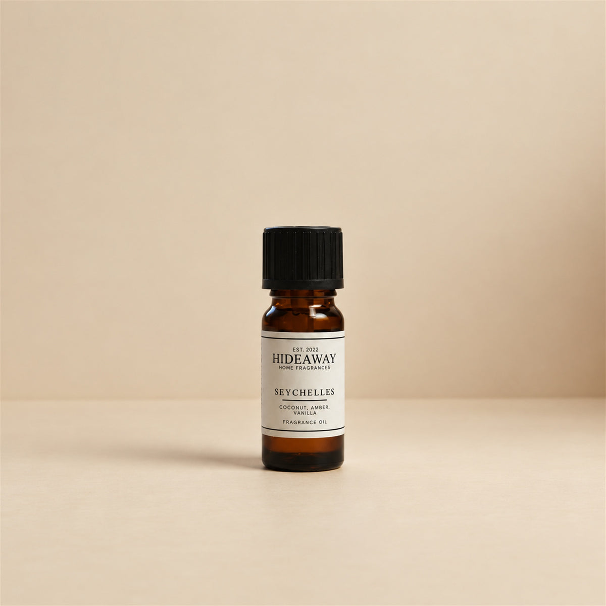Glass dropper dispensing Hideaway Home Fragrances seychelles fragrance oil into an electronic diffuser beside white jasmine petals and coastal decor.
