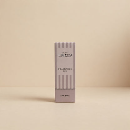 Packaged Hideaway Home Fragrances spa day fragrance oil bottle standing beside its luxury retail box highlighting herbal pine, floral lily, and natural wood notes.