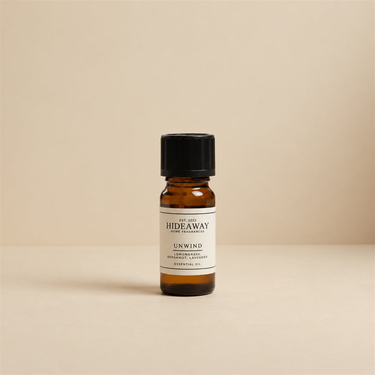 Glass dropper dispensing Hideaway Home Fragrances unwind fragrance oil into an aroma diffuser beside fresh lavender sprigs and soothing candlelight.