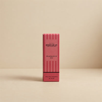 Packaged Hideaway Home Fragrances velvet peony and oud fragrance oil bottle standing beside its luxury retail box highlighting spicy clove, amber, and rich vanilla base notes.
