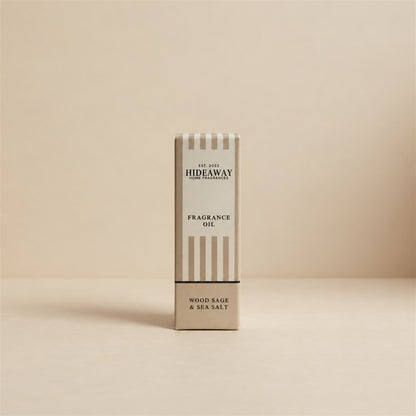 Packaged Hideaway Home Fragrances wood sage and sea salt fragrance oil bottle standing beside its luxury retail box highlighting ambrette seeds, ozone, and cedarwood notes.