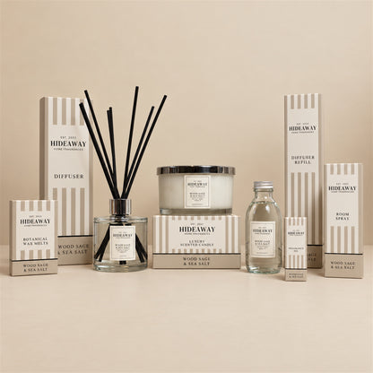 Hideaway Home Fragrances Wood Sage and Sea Salt 3 wick candle burning on a wooden bedside table in a coastal-themed bedroom
