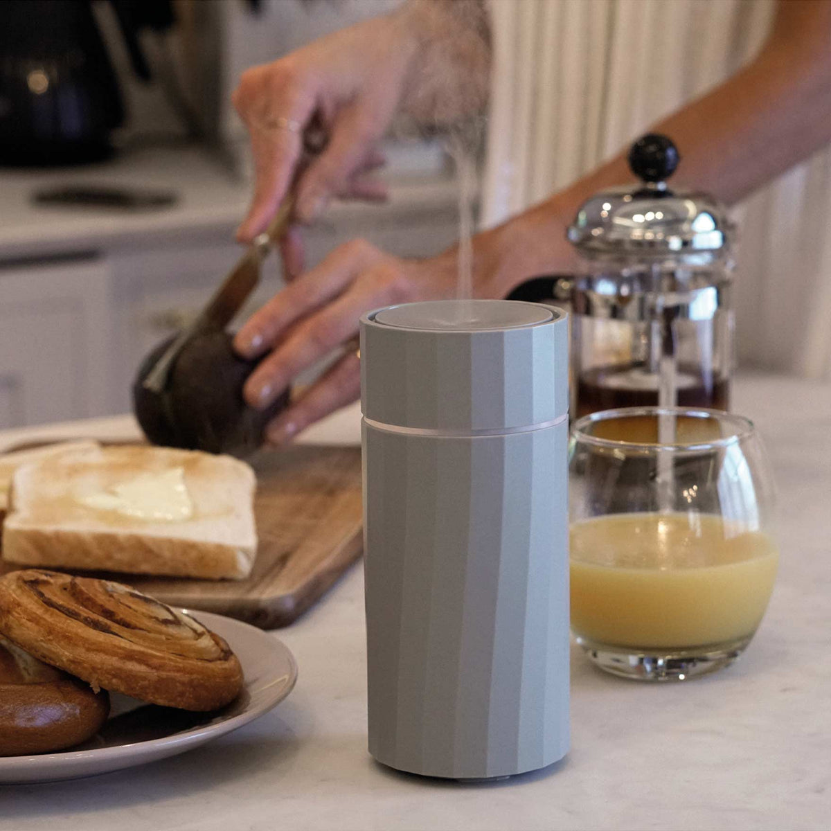Cordless portable Nomad aroma diffuser by Hideaway Home Fragrances being carried effortlessly to an outdoor patio table