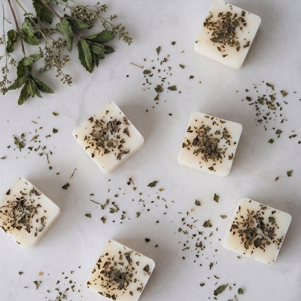 Refreshing thyme and mint wax melt cube melting in a ceramic burner dish by Hideaway Home Fragrances releasing spearmint and tea tree aromas