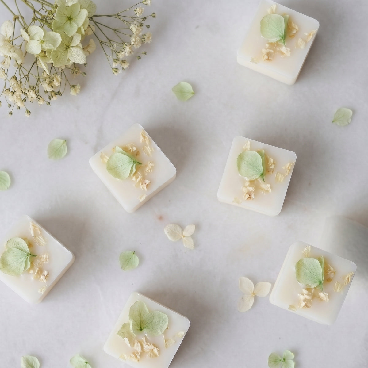 Fresh pear and white freesia wax melt cube warming in a burner dish by Hideaway Home Fragrances releasing sweet melon and rose aromas