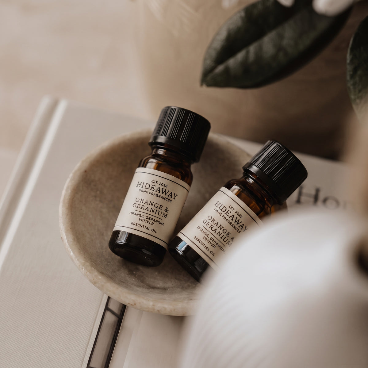 Detailed macro view of the front label branding and glass dropper pipette on the Hideaway Home Fragrances orange and geranium fragrance oil bottle.