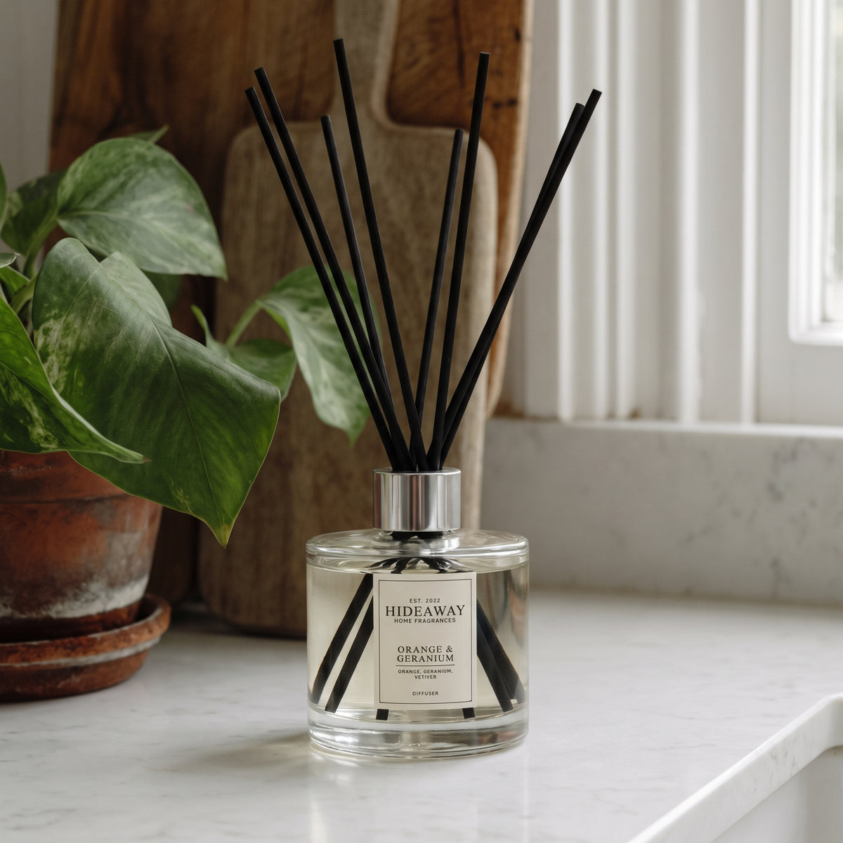 Orange and geranium reed diffuser by Hideaway Home Fragrances featuring citrus, floral, and woody vetiver notes