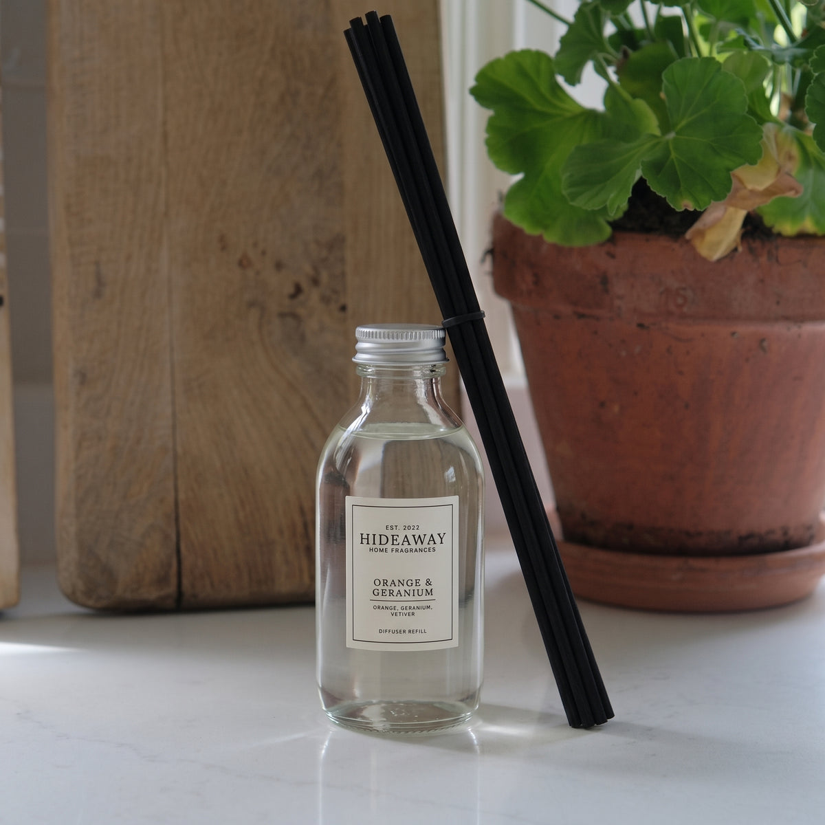 Hideaway Home Fragrances orange and geranium reed diffuser refill liquid bottle showing fragrance notes on label