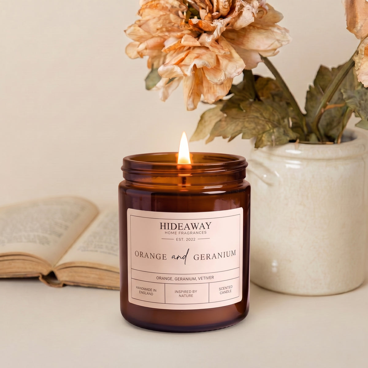 Vibrant orange and geranium amber glass jar candle styled on a sunlit wooden coffee table, Hideaway Home Fragrances