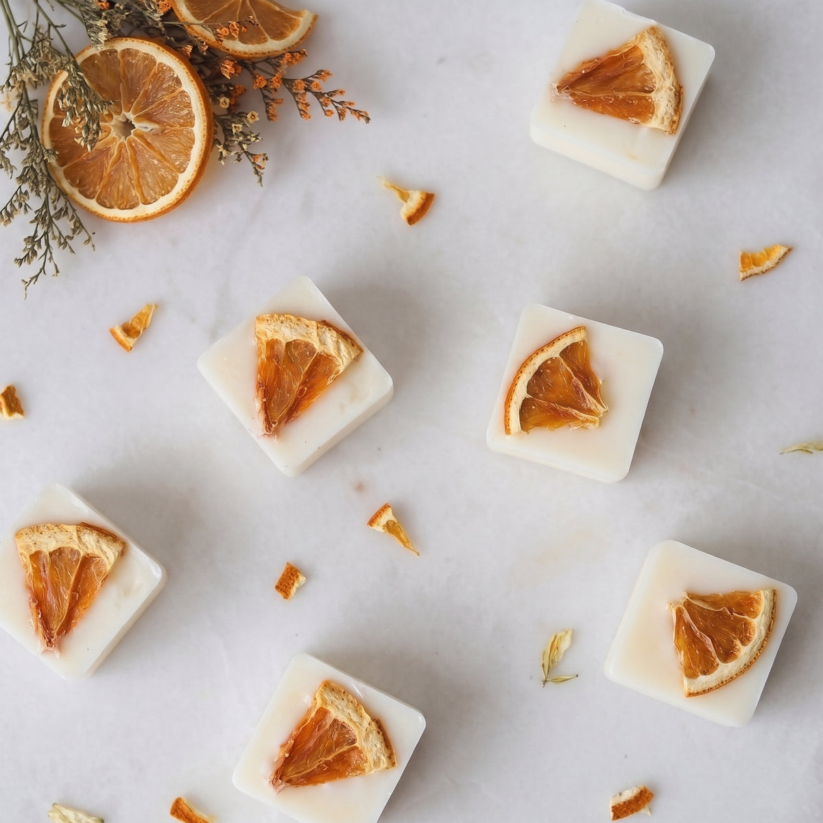 Vibrant orange and geranium wax melt cube melting in a ceramic burner dish by Hideaway Home Fragrances releasing uplifting floral aromas