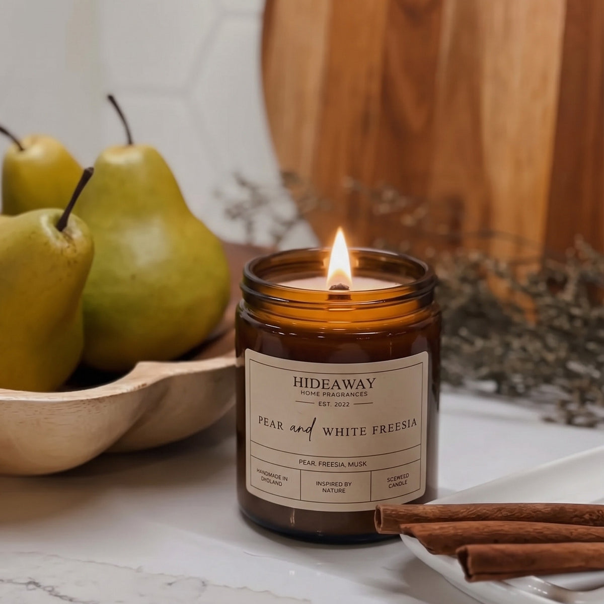 Elegant pear and white freesia amber glass jar candle styled on a sunlit bedside table, Hideaway Home Fragrances