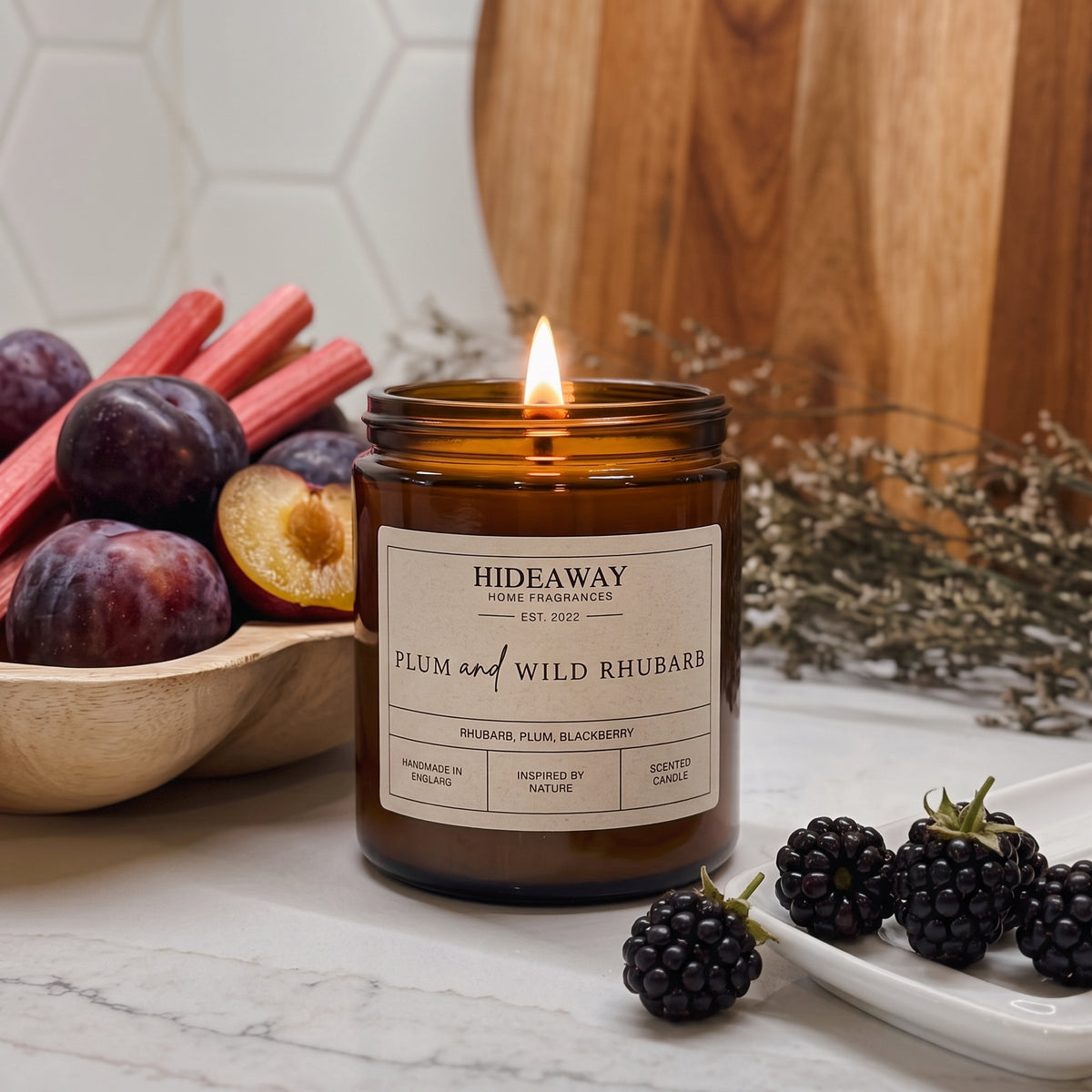 Vibrant plum and wild rhubarb amber glass jar candle styled on a cosy wooden coffee table, Hideaway Home Fragrances