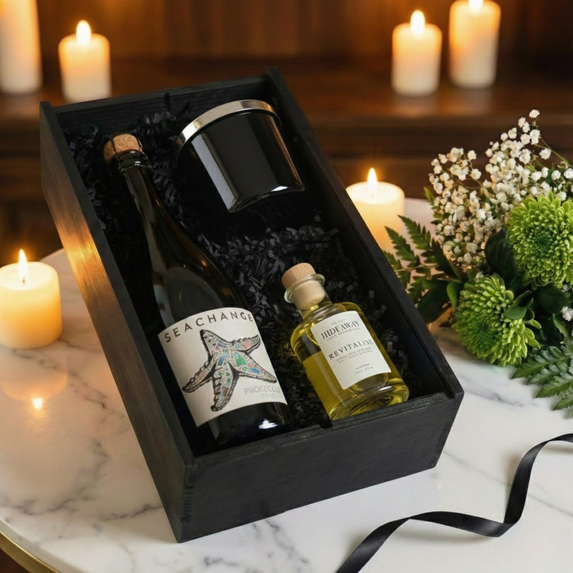 The Ambiance Edit Gift Box featuring Sea Change Prosecco, Hideaway glass candle, and reed diffuser inside a black wooden case.