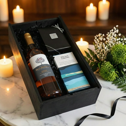 Close up of the open black wooden wine box revealing the Finca Manzanos label and artisan chocolate bar.